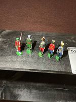 Group of five painted metal toy soldiers on shelf