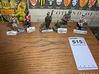 Group of five metal soldier figurines with nameplates displayed on table