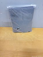 Folded cover in torn clear plastic zipper bag front view