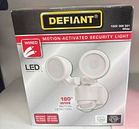 Front of sealed Defiant LED flood light box showing product image and specs