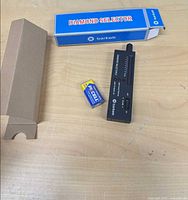Tester, battery and box laid out on table