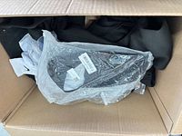 Box showing black garment, Nike socks, black accessory in plastic