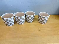 Four identical checkerboard ceramic pots side by side