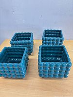 All four teal square ceramic planters side by side