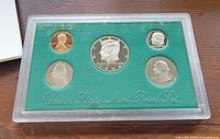 Obverse view of all five coins in sealed plastic lens on green insert