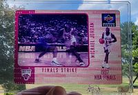 Front of oversized holographic motion card in holder showing Michael Jordan "Finals Strike" design