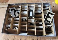 overview of box showing partitioned sections filled with metal character plates