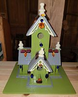Front view of painted wooden birdhouse with gem decorations