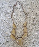 Full view of gold-tone bib necklace with six beige stones