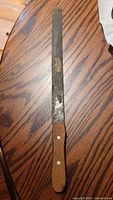 Full view of machete on table showing entire blade and handle