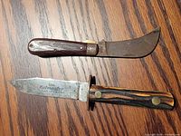 Fixed blade Kutmaster H266 knife and folding pruning knife displayed on wooden surface
