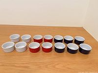 Front view of 12 ramekins in three color groups on wood surface