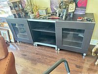 Front view of entire media console showing two glass-door cabinets and centre shelves