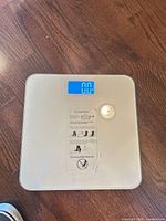 Scale on floor displaying 0.0 with instruction sticker