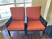 Front view of both orange armchairs showing cushions and frames