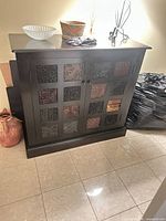 Front view of wood sideboard showing carved square door panels, black frame, dark brown top