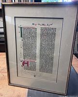 Obverse view of first framed manuscript page showing text column, illuminated initial and frame details