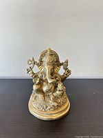 Front view of brass four-armed Ganesha statue on lotus pedestal