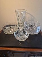 Group shot of four cut-crystal pieces: tall vase, two bowls, and one shallow dish
