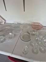 Group view of all clear and pink pressed glass pieces on table