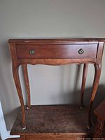 Front view of mahogany veneer side table showing cabriole legs and drawer with brass ring pulls