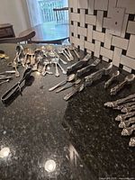 Group view of assorted flatware and serving pieces spread on countertop