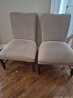 Front view of both beige upholstered dining chairs