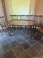 oval solid wood dining table with six Windsor chairs around it