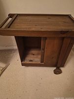 Full view of wooden bar cart showing top tray, side panel, cabinet opening and two casters
