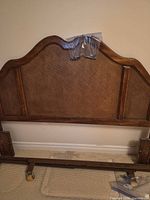 Full front view of headboard showing arched profile, rattan panel and attached hardware bag