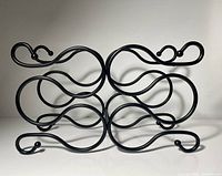 Front view of black scroll metal wine rack showing six cradle spaces