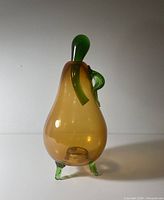 Full view of pear container with lid attached showing amber body and green feet