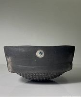 side profile of black pottery bowl showing textured rounded base and matte finish