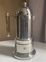 Full view of moka pot showing stainless body and brass accents