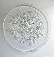 Full view of round clear glass platter showing complete floral and butterfly relief design