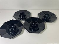 Four black octagonal egg cups displayed top view