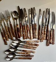 Complete set laid out: forks, knives, large spoons, teaspoons