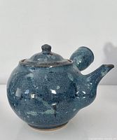 Right side view of blue ceramic teapot with side handle and lid