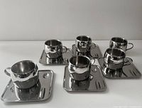 all six stainless steel cups grouped on five square trays