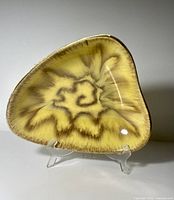Top view showing yellow-brown drip glaze starburst design and gilded rim