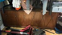 Front view of walnut veneer blanket chest under hanging clothes