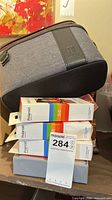 Full lot showing Switch case atop stack of Polaroid paper packs and other boxed items