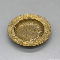 Angled view of brass dish showing engraved surface and patina