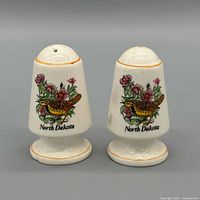Front view of both ceramic shakers showing North Dakota bird and floral design