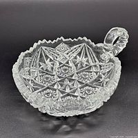 Top view of clear pressed glass dish showing hobstar pattern and handle