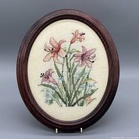 Front view of stitched floral artwork in oval wooden frame