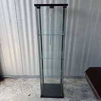 Front view of tall glass curio cabinet showing shelves and power cord