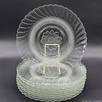 Stack of eight pressed glass plates showing rim pattern