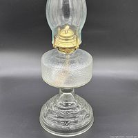 Front view showing embossed glass base, textured font, brass burner and chimney