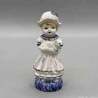 Front view of porcelain figurine showing girl holding cat, colors and detailing visible